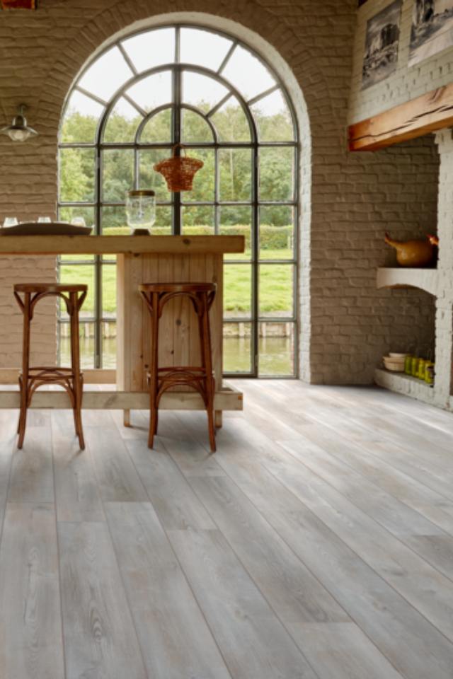 Tuscan Inspired dining area with wood look flooring and arched window and exposed brick wall